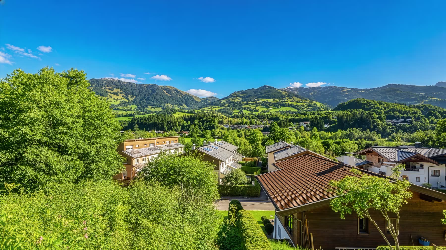 Panorama über Kitzbühel mit Chalets im Vordergrund und Bergkette im Hintergrund