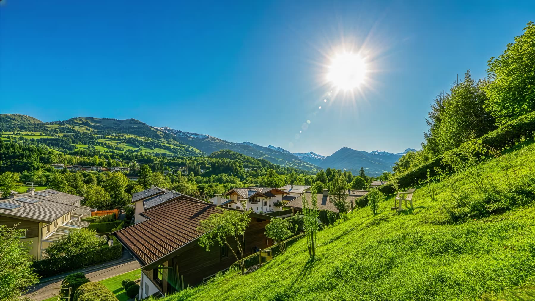 Sonniger Hang oberhalb von Kitzbühel mit Blick über Chalets auf die umliegenden Berge